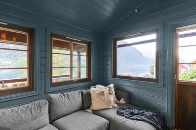 a couch in a room with three windows at Cabin alongside the beautiful fjærlandsfjord in Fjarland