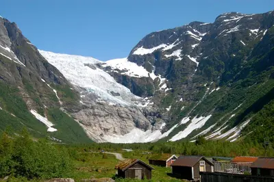 a snow covered mountain with houses in front of it at Cabin alongside the beautiful fjærlandsfjord in Fjarland