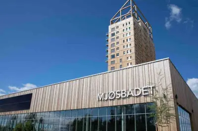 a large building with a skyscraper in the background at Mjøssuite with lovely view in Ringsaker