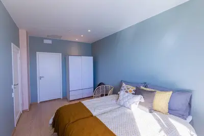 a bedroom with a bed and a blue wall at Mjøssuite with lovely view in Ringsaker