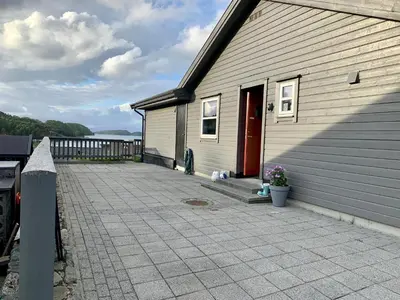 a house with a driveway and a red door at Exclusive fjordside villa with swimming pool, sauna, jacuzzi and boat hire in Sveio
