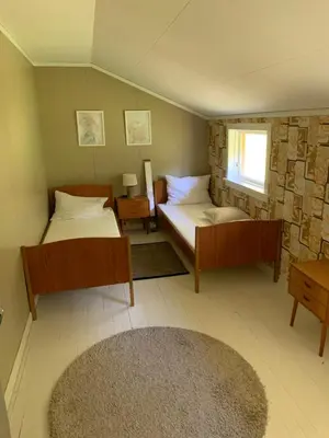 a bedroom with two beds and a window and a rug at Dispen feriehus in Stryn