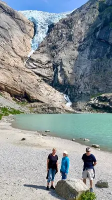 three people standing on a beach near a mountain at Dispen feriehus in Stryn