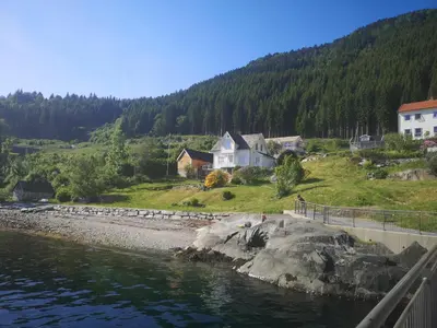 a house on a hill next to a body of water at Feriehus med badestamp in Lavik