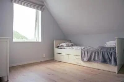a bedroom with a bed and a window at Feriehus med badestamp in Lavik