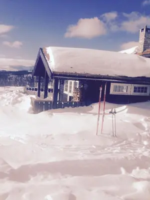 a house covered in snow with skis in front of it at Storemyr by Norgesbooking - cabin with amazing view in Hol