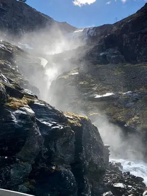 a misty waterfall in a mountain with a road at Åndalsnes Sentrum 1-room Apartment in Åndalsnes