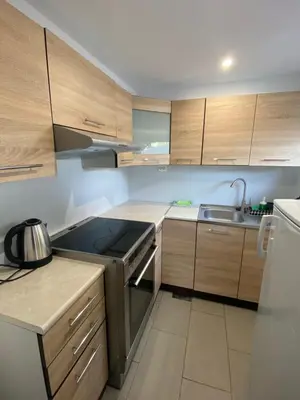 a small kitchen with wooden cabinets and a sink at Sukkertoppen Apartment in Ålesund