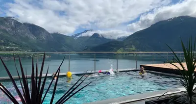 a group of people in a swimming pool with mountains at Olden Studioapartment in Olden