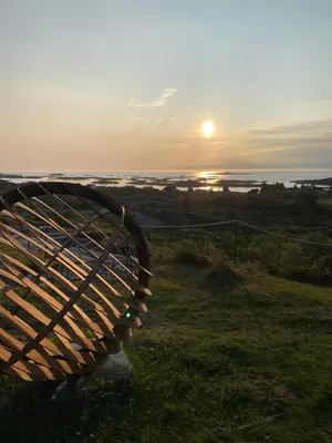 a wooden bench sitting on top of a field with the sunset at Atlantic Panorama in Vevang