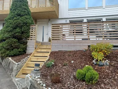 a garden with a wooden bench in front of a house at Nature View Apartment in Espeland in Bergen