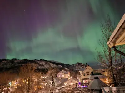 an aurora dances in the sky above a house at Nature View Apartment in Espeland in Bergen