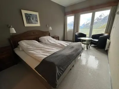 a bedroom with a bed and chairs and a window at Hotel Videseter in Stryn