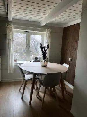 a dining room table with chairs and a vase with flowers at Indreli feriehus in Flåm
