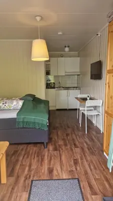 a room with a bed and a table and a kitchen at Kvamsdal Pensjonat 2 in Eidfjord