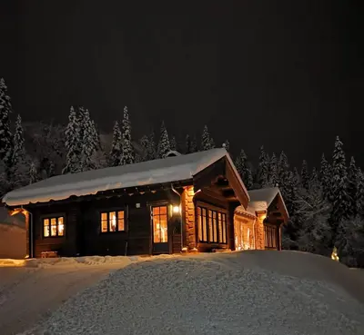 a log cabin in the snow at night at Liaplassen Timber Lodge in Beitostøl