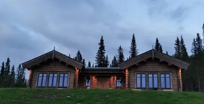 a log home on a hill with trees in the background at Liaplassen Timber Lodge in Beitostøl
