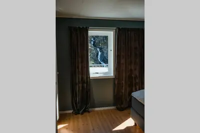 a room with a window with curtains and a wooden floor at Vestly in Etnesjøen