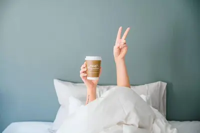a person is laying in bed with a cup of coffee at Vestly in Etnesjøen