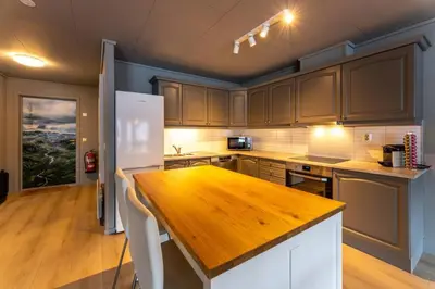 a kitchen with a wooden table and a white refrigerator at Langfoss in Etnesjøen
