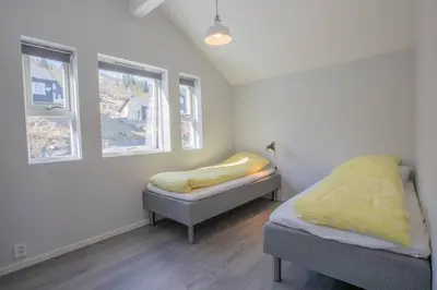a bedroom with two beds and two windows at Fosskamben 1 Moderne hytte ikkje langt frå Sogndal in Sogndal