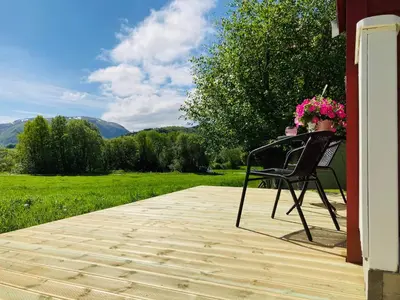 a woman sitting in a chair with flowers on a porch at Rødseth gårdsovernatting Hytter in Molde