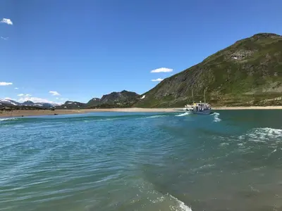 a boat in the water next to a beach at Jotunheimen Arctic Domes in Beitostøl