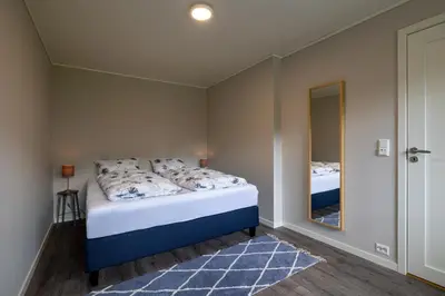 a bedroom with a bed with a mirror and a blue and white bed at Flotunet - Jørnhuset in Stryn