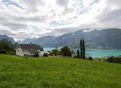 a house on a hill with a lake and mountains at Flotunet - Jørnhuset in Stryn