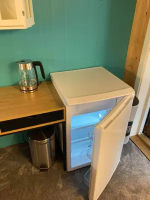 a small refrigerator with its door open next to a table at Rødseth Gårdsovernatting Familierom in Molde