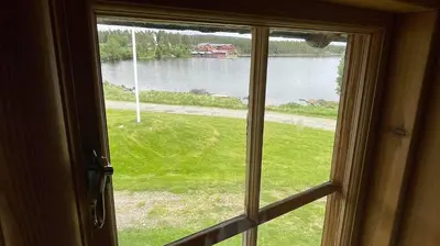 a window looking out at a view of a lake at Gammelstua ved Femund in Elga