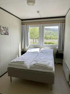 a bed in a room with a large window at Karivollen Overnatting in Melhus