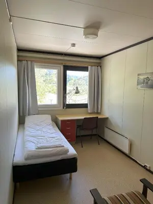 a bedroom with a bed and a desk and a window at Karivollen Overnatting in Melhus