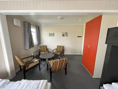 a room with chairs and a table and a red door at Karivollen Overnatting in Melhus