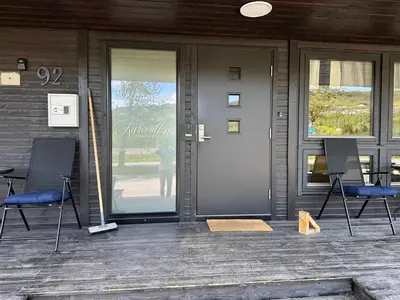 a porch with two chairs and a door on a house at Karivollen Overnatting in Melhus