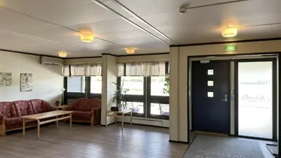 a lobby with two chairs and a door and windows at Karivollen Overnatting in Melhus