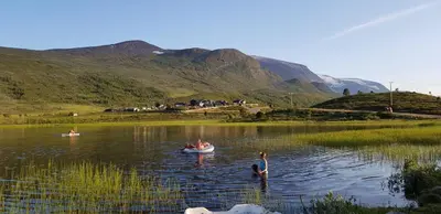 a group of people swimming in a lake at Raubergstulen fjellstue og hytter in Boverdalen