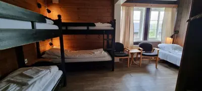 a room with four bunk beds and a table and chairs at Raubergstulen fjellstue og hytter in Boverdalen