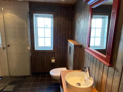 a bathroom with a sink and a toilet and windows at Løstegård Cabins in Gol