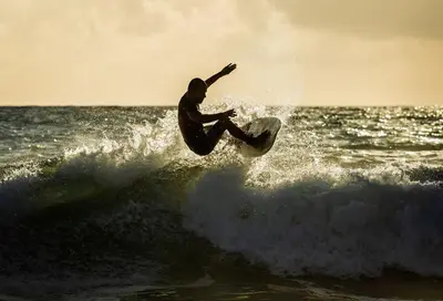 a man riding a wave on a surfboard in the ocean at Småstranda Fjord Lodge in Åheim