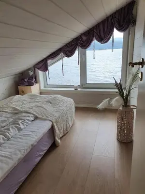 a bedroom with a bed and a large window at Småstranda Fjord Lodge in Åheim