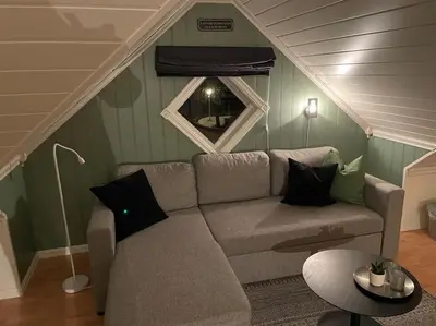 a living room with a couch and a window at Koselig garasjeloft! in Holen