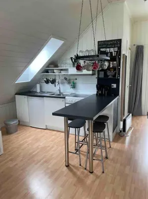a kitchen with a table and chairs in a room at Koselig garasjeloft! in Holen