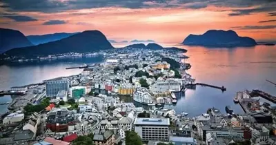 a city on the water with mountains in the background at Koselig garasjeloft! in Holen