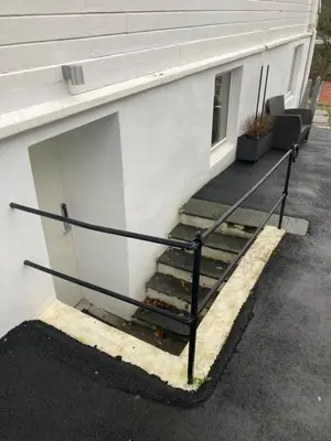 a set of stairs next to a white building at Kjellerleilighet - nært Haukeland sykehus. in Bergen