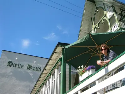 a woman sitting on a balcony of a building at Hjelle Hotel in Hjelle