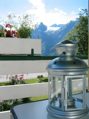 a glass lantern on a table with a view of mountains at Hjelle Hotel in Hjelle