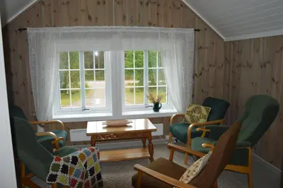 a living room with chairs and a window and a table at Fulufjellet nationalpark Lodge - Home of snow, nature and peace in Ljørdalen