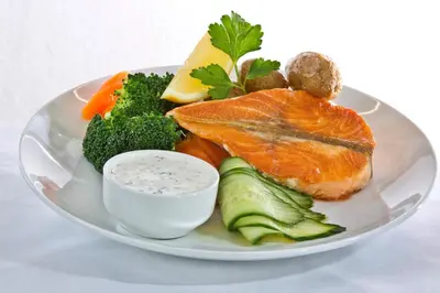 a plate of fish and vegetables with a dipping sauce at Lillehammer Hostel in Lillehammer