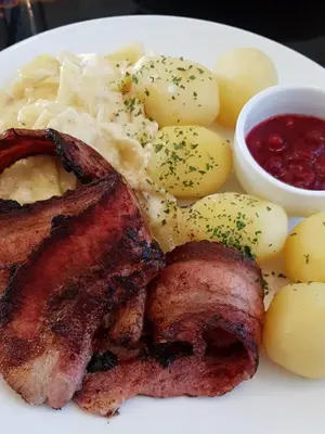 a plate of food with meat potatoes and sauce at Lillehammer Hostel in Lillehammer